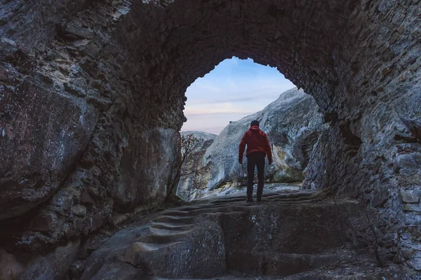 Figura dell'uomo che attraversa l'arco di pietra all'alba — Foto Stock