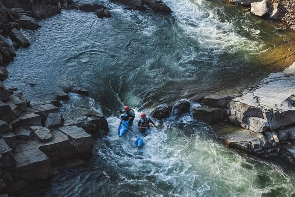 Dos hombres en catamarán de aguas bravas están atravesando el rápido río de la montaña a principios de primavera Imagen de stock