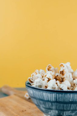 Tahtaya yerleştirilmiş seramik kasede dikey patlamış mısır.