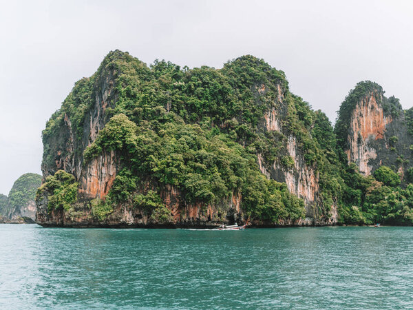 The sea surrounded by rocky hills covered in greenery and fog at daytime