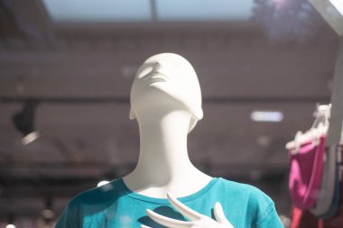 Mavi tişörtlü bir vitrindeki mankenler yukarı bakıyor.