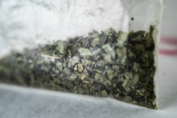 green dry crushed leaves (marijuana, tobacco) in a plastic bag