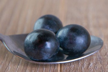 Mavi üzümler kaşığın üzerinde, yumuşak odak noktasında.