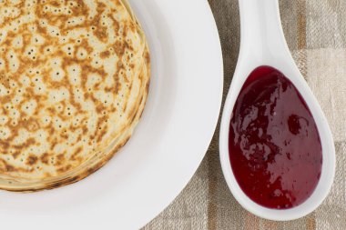 Karnaval kutlaması: taze pişmiş gerçek Rus krepleri yoğurt, beyaz tabak ve siyah frenk üzümü reçeli. Keten masa örtüsü, ön manzara, kapat