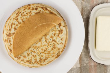 Karnaval kutlaması: taze pişmiş gerçek Rus gözlemeleri yoğurtla yapılır, beyaz bir tabakta, tereyağında. Keten masa örtüsü, kapat