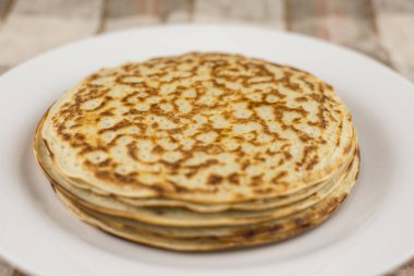 Karnaval kutlaması: Beyaz bir tabakta yoğurtla yapılan taze pişmiş gerçek Rus gözlemeleri. Keten masa örtüsü, ön manzara.