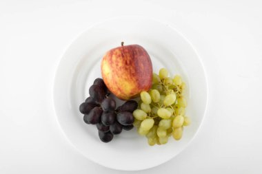 Vejetaryen diyeti: farklı üzümlerden yaşam ve beyaz bir tabakta olgun elma. beyaz arkaplan