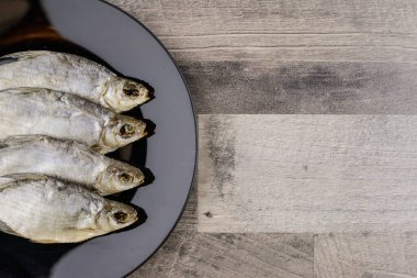 bira aperatifi: 4 güneşte kurutulmuş tatlı su siyah tabakta tuzlu balık - vitamin ve protein kaynağı, gri masa, serbest alan