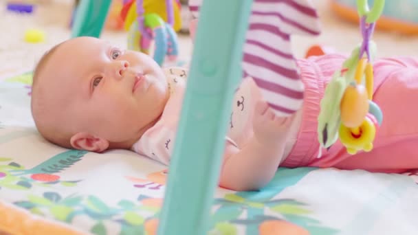 撮影新生児の女の子はカラフルなおもちゃでベッドに横たわっている — ストック動画