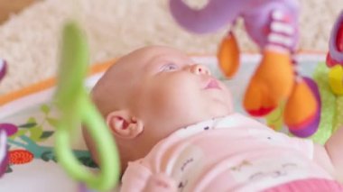 Çekim yeni doğan kız bebek renkli oyuncaklar ile yatakta yatıyor