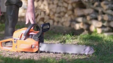 Oduncu testereyi çalıştırıyor ve çalışmaya hazırlanıyor. Elektrikli testere çalıştırılıyor. 