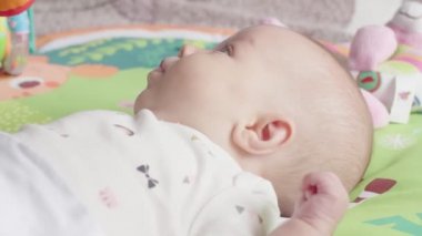 Çekim yeni doğan kız bebek renkli oyuncaklar ile yatakta yatıyor