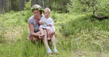 Küçük kız bir yaşında dünyayı tanımaya başlıyor. Küçük bir kızın portresi, bir yaşında, büyükannesiyle orman arka planında.