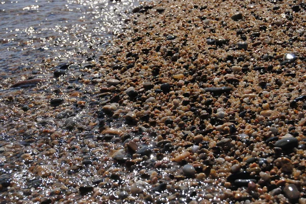 Vlny a průhledná voda na písku na pláži. Textury. vodní pěna. Slunečný den — Stock fotografie