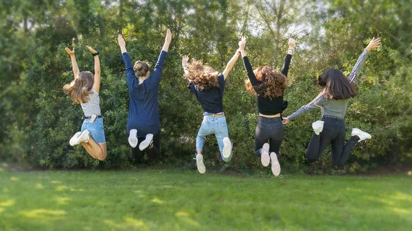 Банда девочек прыгает. Счастливый момент в жизни и идеальный момент и место. Молодые друзья веселятся в парке. Многообразие. Дружба. единство и разнообразие — стоковое фото
