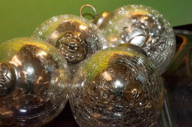 Parlak gümüş ve altın renkli küreler ya da Noel süsleri yakın çekimde gösteriliyor.