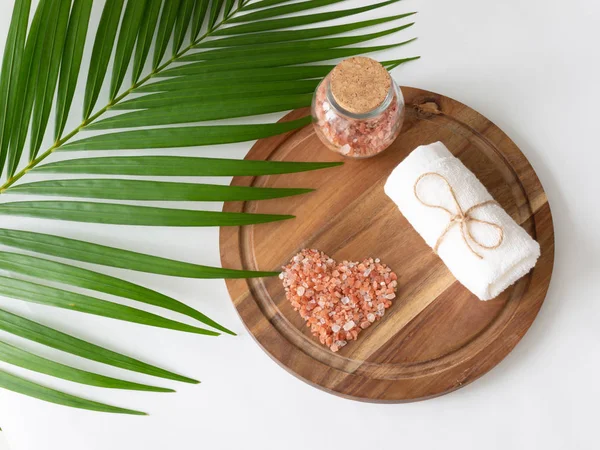 Розовая гималайская соль и полотенце на деревянной доске, монстре и пальме — стоковое фото