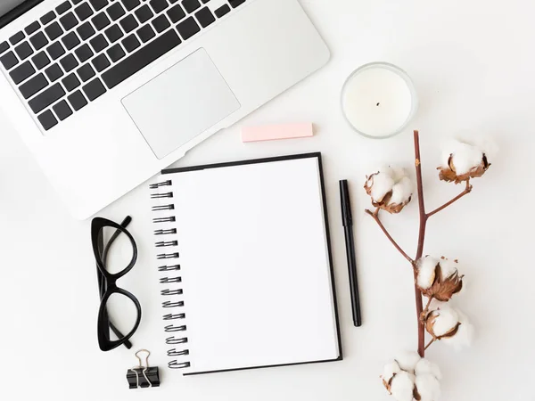 Laptop, eyeglasses, candle, notepad and pen.