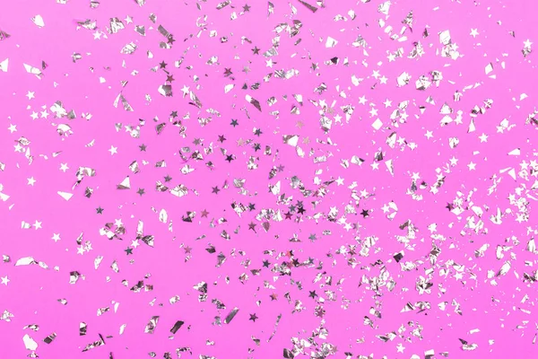 Stříbrný foliový konfety na neonové růžové pozadí. — Stock fotografie