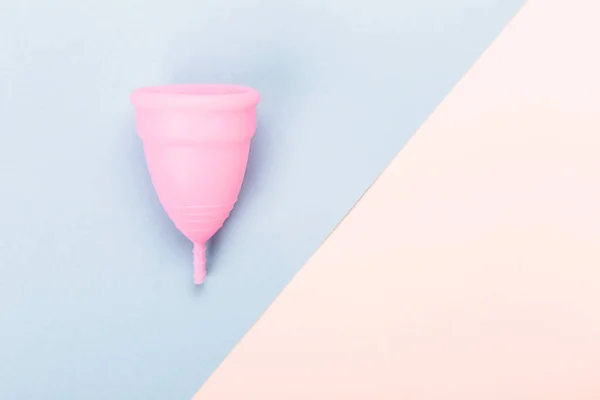 Copa menstrual rosa sobre fondo azul y amarillo . — Foto de Stock