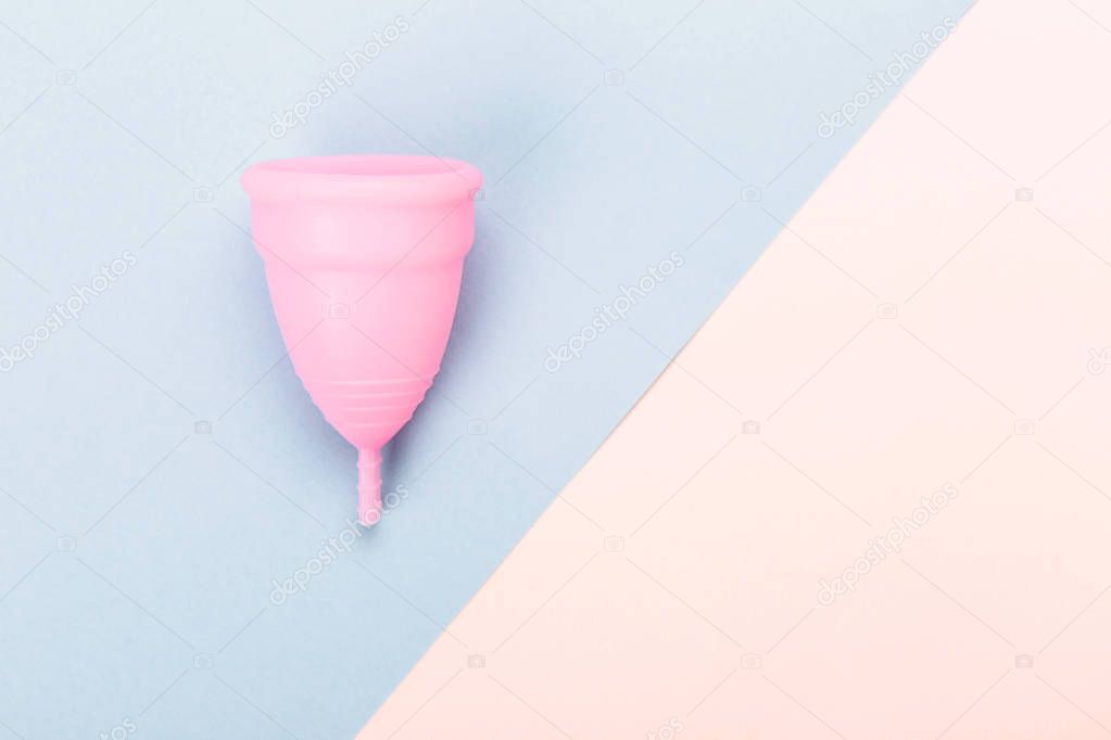 Pink menstrual cup on blue and yellow background.