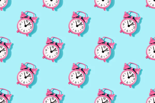 Seamless pattern made with pink alarm clock on turquoise backgro