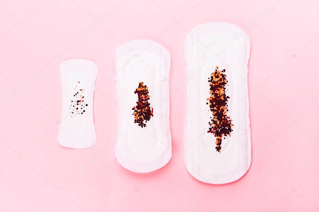 Three sanitary pads on pink background.