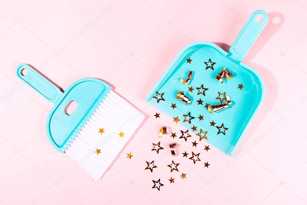 Turquoise broom and dustpan on pastel pink background.