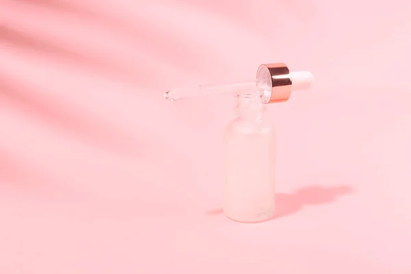 Hermosa toma de una botella de suero sobre fondo rosa . — Foto de Stock