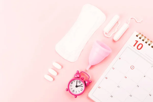 Calendario, copa menstrual, toalla sanitaria y pastillas . — Foto de Stock
