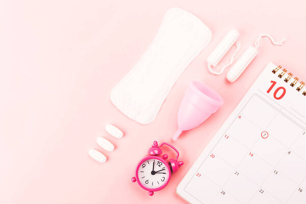 Calendar, menstrual cup, sanitary pad and pills.