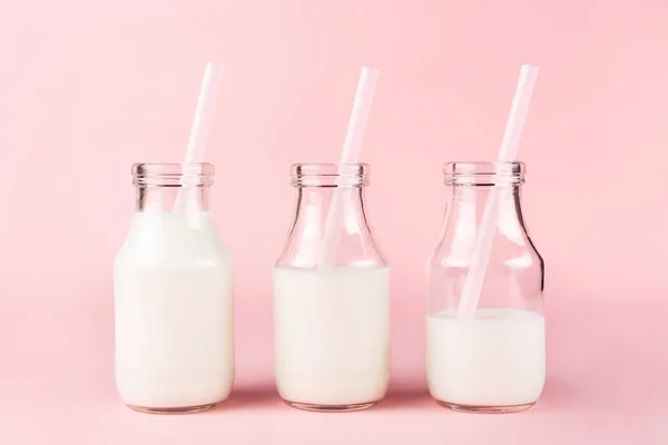 Tres botellas de leche de yogur sobre fondo rosa . — Foto de Stock