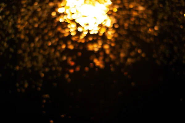 Blurred gold falling sparkles on black background.