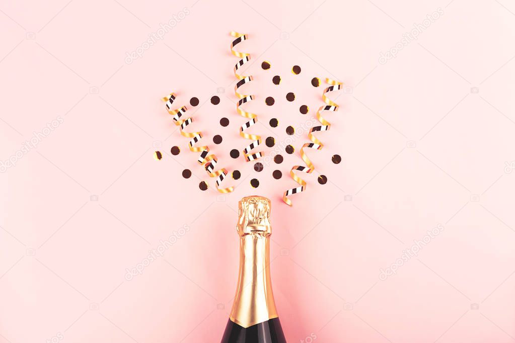 Creative New Year composition with champagne bottle and confetti on pastel pink background.