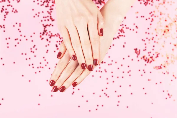 Deux mains de femme et confettis tombant sur fond rose. — Photo