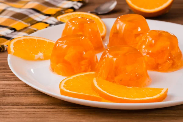 Orange jelly and orange slices on a plate on a wooden table