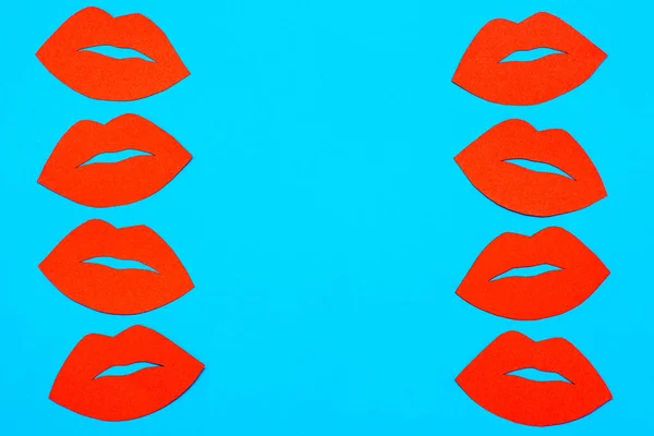 World Kiss Day. Red lips from cardboard in two rows on a blue background. Copy space