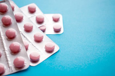 Pembe tablet gümüş Vakumlu ambalaj mavi zemin üzerine kapatın. Kullanılmayan ya da süresi dolan reçeteli ilaçlar. Güvenli değil almak ilaç kullanım süresi. Seçici odak