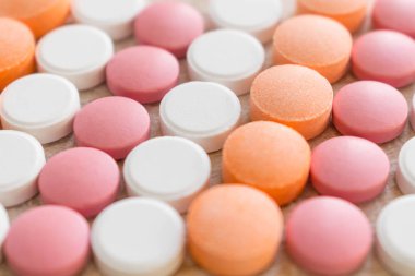 Beyaz, pembe ve turuncu tablet çizgili arka plan. Farklı asit giderici ilaçlar mide asidi nötralize yardımcı olur. Antiasit Oral: Kullandığı, yan etkileri, etkileşimleri, riskleri, uyarılar. Seçici odak