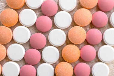 Beyaz, pembe ve turuncu tablet çizgili arka plan. Farklı asit giderici ilaçlar mide asidi nötralize yardımcı olur. Antiasit Oral: Kullanır, yan etkileri, etkileşimleri, riskleri, uyarılar