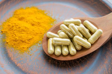 Doğal bitki gıda ek zerdeçal bitkisel kapsül ve turuncu curcumin toz kil plaka üzerinde kaşıkla. Organik zerdeçal özü, köri ayıklamak, Diferuloylmethane, Jianghuang, Curcuma Longa