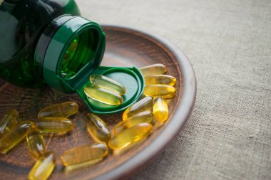 Sarı akşam çuha çiçeği tohumu petrol jelatin kapsül ve kil plaka çuval bezi zemin üzerine yeşil şişe. Evening Primrose yağı Softgels. BDT-linoleik asit, yağ asitleri, Gamma-linolenik asit (Gla)