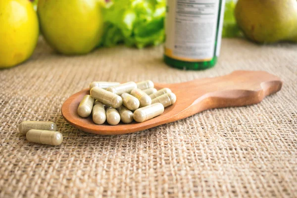 Ekinezya: Bitkisel bağışıklık güçlendirici kapsül. Hapları Immünomodülatör. Ekinezya tablet şişe tabletleri, yeşil meyveler ve otlar bir arka plan üzerinde bir tahta kaşık.