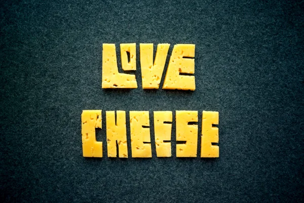 爱奶酪文本字在黑暗的背景 把黄色的切达干酪刻成字母 奶酪排版 食品刻字 — 图库照片