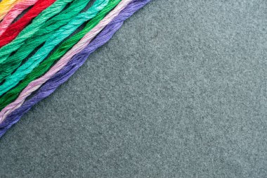 Parlak renkli nakış iplikçikleri. Koyu renk keçeli kumaş üzerine işlenmiş çok renkli iplikler. El yapımı nakış işleme arka planı