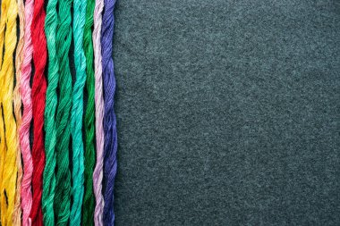 Parlak renkli nakış iplikçikleri. Koyu renk keçeli kumaş üzerine işlenmiş çok renkli iplikler. El yapımı nakış işleme arka planı