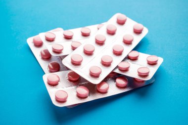 Tıp pembe hapları veya simli kabarcıklar mavi zemin üzerine tablet. Tedavi ilaç tedavisi için ilaç reçete. Antibiyotik, ağrı kesici portre. İlaç ilaç, sağlıklı, eczane ve sağlık kavramı. 
