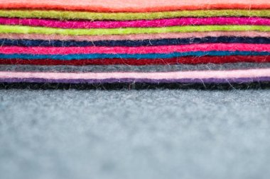 Farklı renk gri kumaş üzerine keçe flep yığını arka plan bulanık. Renkli yığını flep gri kumaş üzerinde hissetti. El yapımı, dikiş, dikiş arka plan, yaratıcılık, el sanatları,