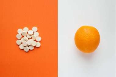 Minimalist tarzı C vitamini kavram. Doğal vitamin turuncu vs sentetik vitamin hap. Doğal ve sentetik bir şekilde sağlık hizmetleri arasında seçim. Besin takviyesi