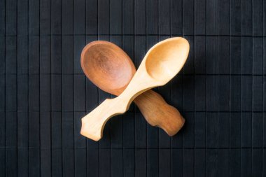 İki farklı ahşap ve farklı boyutları üzerinde siyah bir ahşap arka plan boş el yapımı tahta kaşıklar geçti. Güzel ev yapımı kaşık bir rustik tarzda. Ahşap oyma zanaat